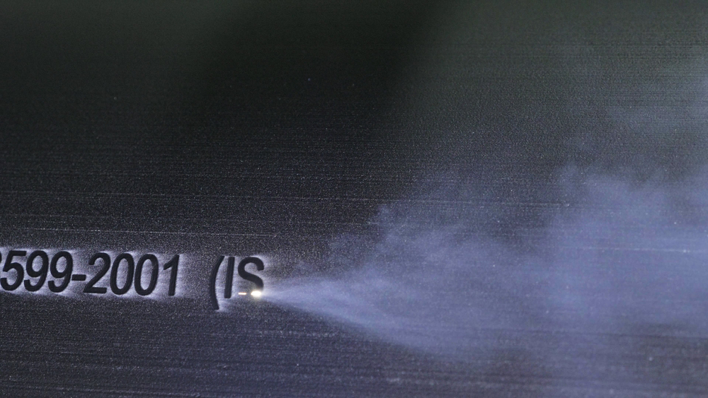 A laser engraving machine is burning a serial number into a work piece