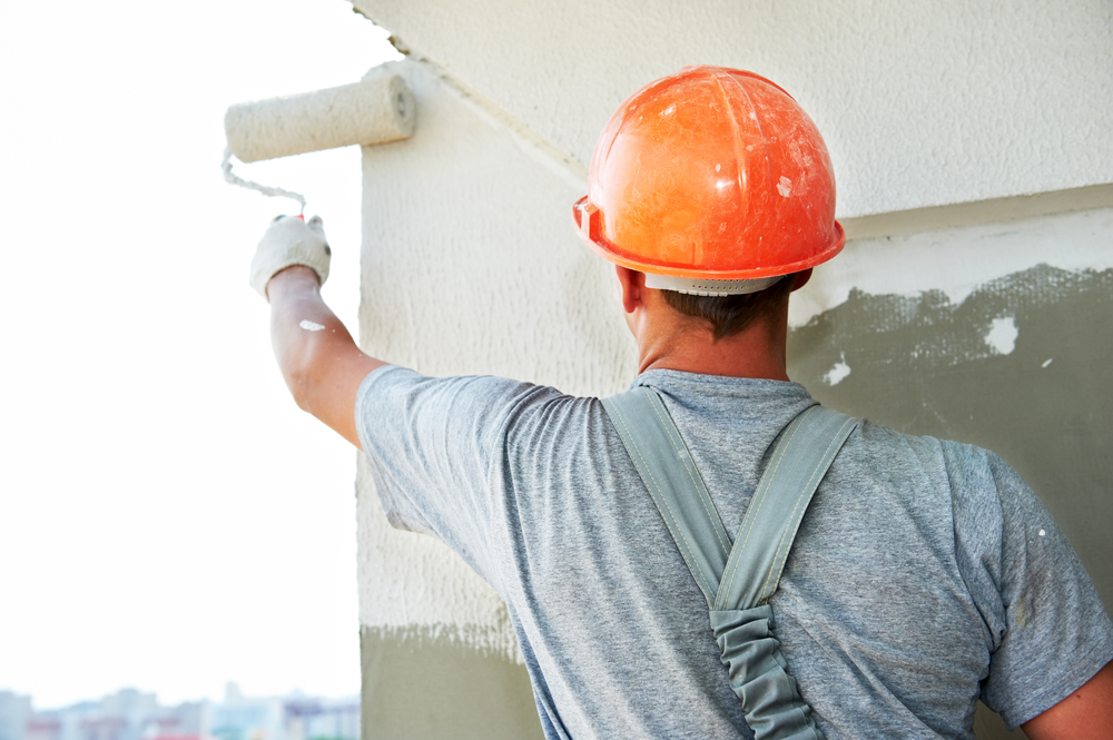 Construction worker in hard hat painting a wall