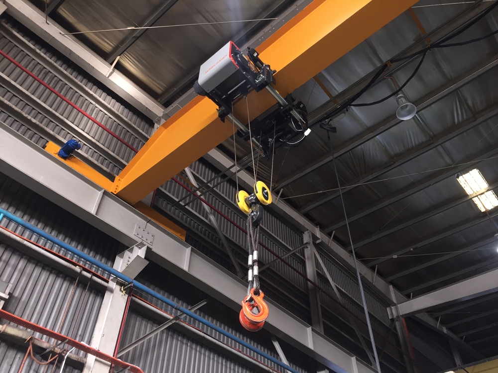 A picture of a large, overhead crane in a factory or warehouse.  Also called a gantry robot.  