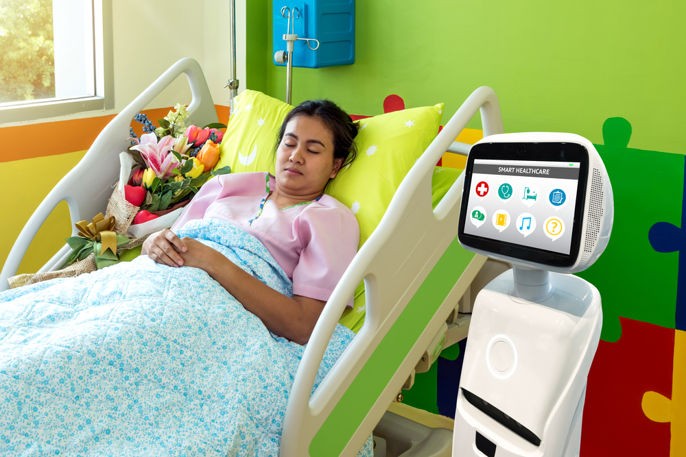 Female patient sleeps in hospital bed with robot next to her. The robot is white and has a display with Smart Healthcare options.